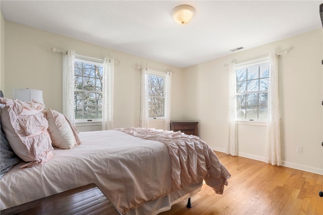 bedroom with multiple windows and light wood-type flooring