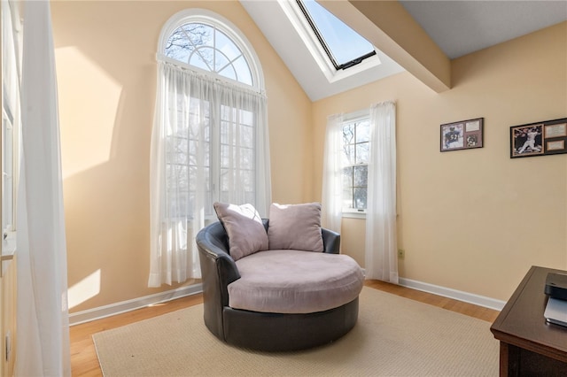 living area featuring lofted ceiling with skylight and light hardwood / wood-style flooring