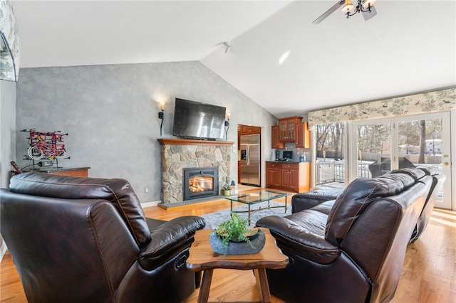 living room featuring ceiling fan, a fireplace, vaulted ceiling, and light hardwood / wood-style flooring