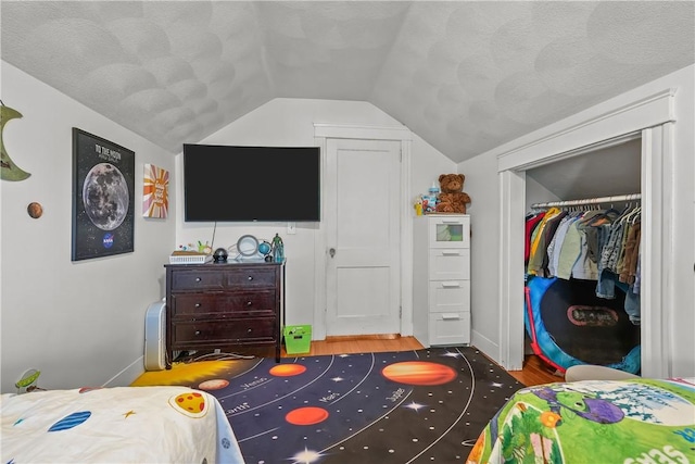 bedroom featuring lofted ceiling, dark wood-type flooring, a closet, and a textured ceiling