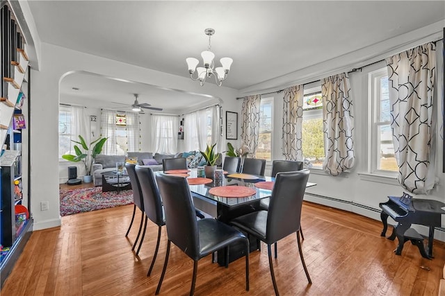 dining room featuring baseboard heating, wood-type flooring, and ceiling fan with notable chandelier