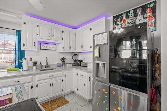 kitchen with white cabinetry, sink, and stainless steel refrigerator