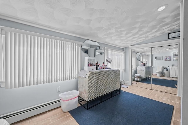 bedroom featuring a baseboard radiator, a textured ceiling, and vaulted ceiling