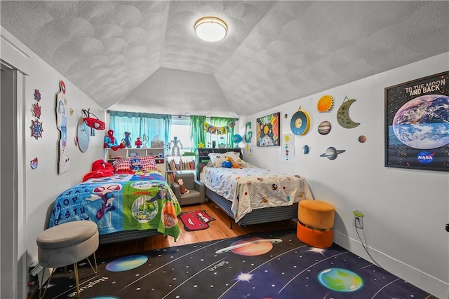 bedroom featuring lofted ceiling, hardwood / wood-style floors, and a textured ceiling