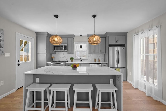 kitchen with a kitchen island, appliances with stainless steel finishes, sink, and light stone counters