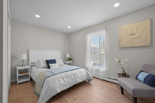 bedroom with a baseboard heating unit and light wood-type flooring