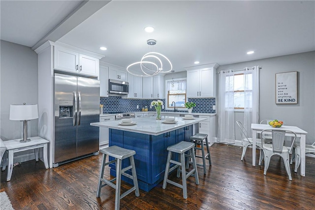 kitchen featuring white cabinetry, decorative light fixtures, dark hardwood / wood-style floors, and appliances with stainless steel finishes