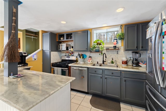 kitchen featuring appliances with stainless steel finishes, sink, gray cabinetry, and decorative backsplash