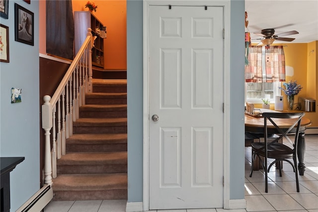 stairs featuring baseboard heating, ceiling fan, and tile patterned floors