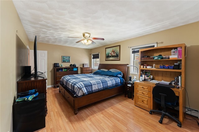 bedroom with a textured ceiling, light hardwood / wood-style flooring, and ceiling fan