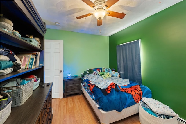 bedroom featuring a baseboard radiator, light hardwood / wood-style floors, and ceiling fan