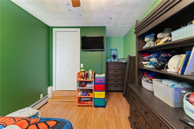 bedroom with light hardwood / wood-style flooring, a baseboard radiator, and ceiling fan