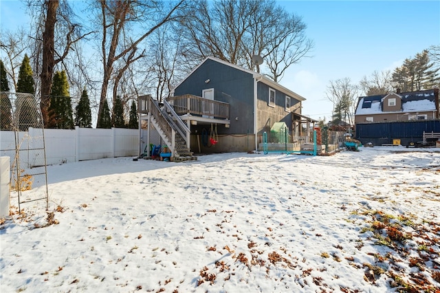 snow covered back of property featuring a deck