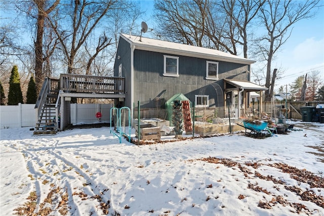 snow covered back of property with a wooden deck