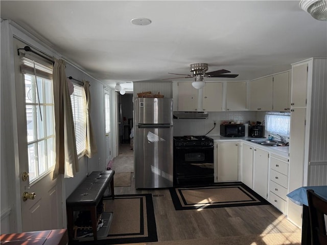 kitchen featuring white cabinetry, sink, backsplash, dark hardwood / wood-style flooring, and black appliances