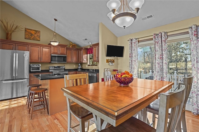 dining area featuring an inviting chandelier, sink, light hardwood / wood-style flooring, and vaulted ceiling