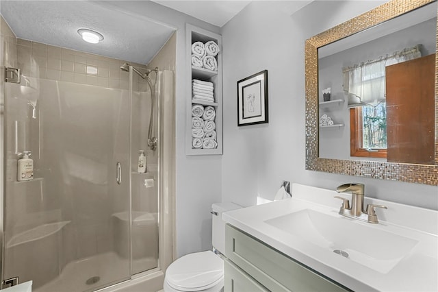 bathroom featuring vanity, toilet, a shower with door, and a textured ceiling