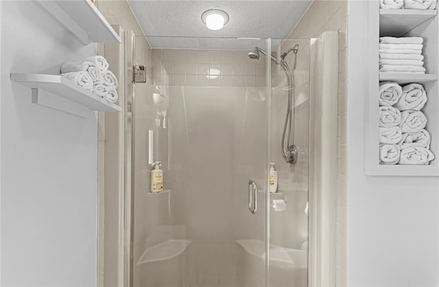 bathroom featuring a textured ceiling and a shower with shower door