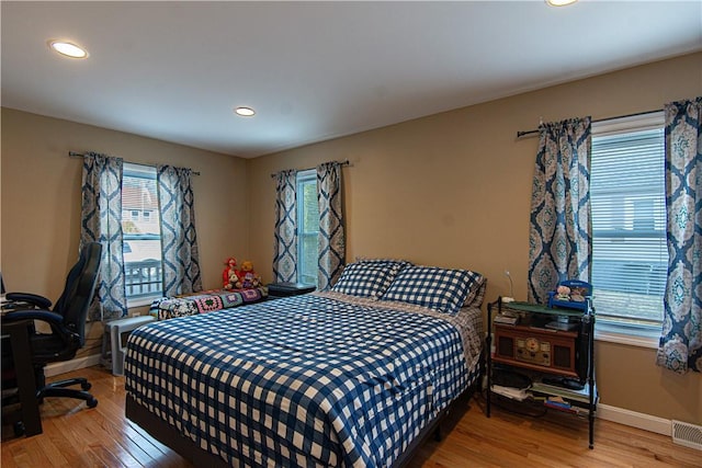 bedroom with wood-type flooring and multiple windows