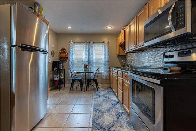 kitchen featuring stainless steel appliances, light tile patterned flooring, sink, and backsplash