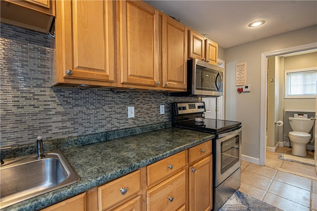 kitchen with sink, appliances with stainless steel finishes, backsplash, light tile patterned flooring, and dark stone counters