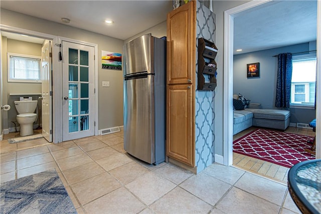 kitchen featuring light tile patterned flooring, a healthy amount of sunlight, and stainless steel fridge