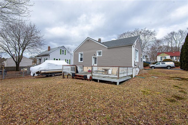 back of property with a wooden deck and a lawn