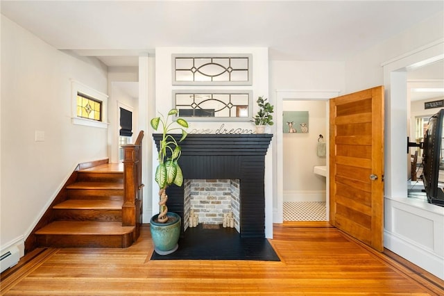 stairway with hardwood / wood-style floors and a baseboard heating unit