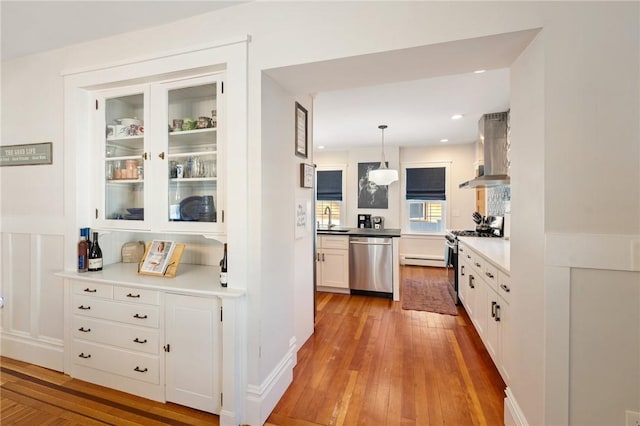 kitchen with sink, island range hood, decorative light fixtures, stainless steel appliances, and white cabinets