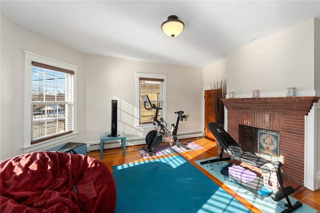 exercise room featuring hardwood / wood-style floors, a fireplace, and baseboard heating