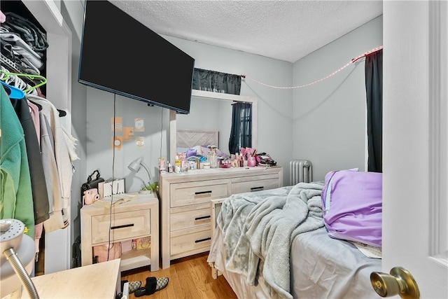 bedroom featuring radiator, a textured ceiling, and light hardwood / wood-style flooring