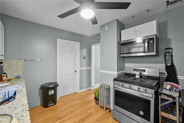 kitchen with ceiling fan, appliances with stainless steel finishes, tasteful backsplash, light stone countertops, and white cabinets