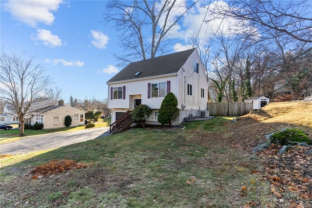 view of front of property with a garage, a storage unit, a front lawn, and central air condition unit