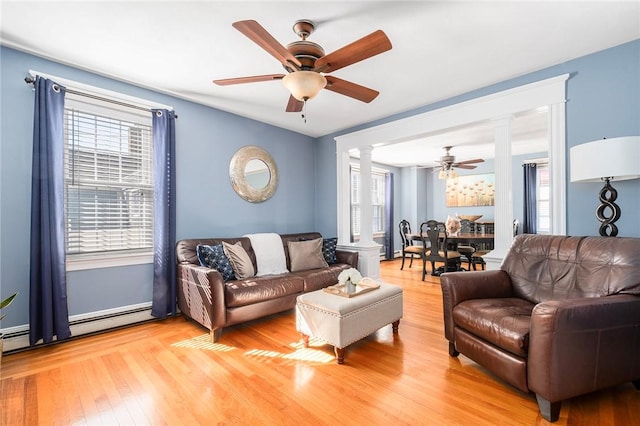 living room with baseboard heating, ceiling fan, light hardwood / wood-style floors, and ornate columns