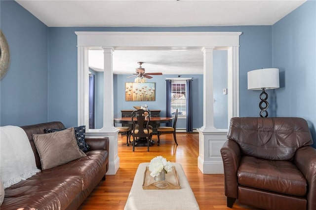 living room featuring decorative columns, light hardwood / wood-style floors, and ceiling fan