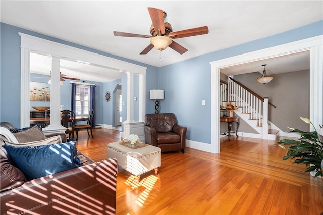 living room featuring wood-type flooring, decorative columns, and ceiling fan