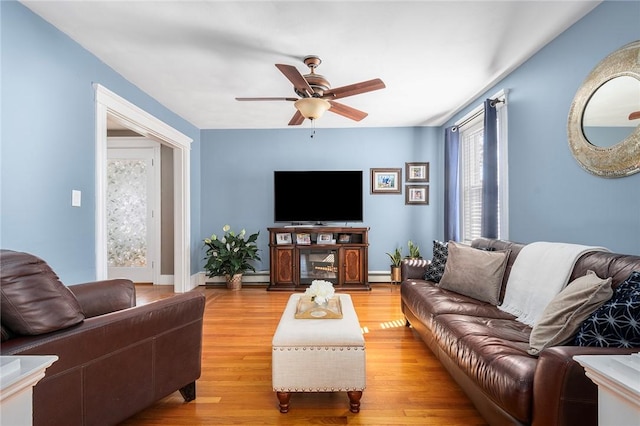 living room featuring ceiling fan, a baseboard radiator, and light wood-type flooring