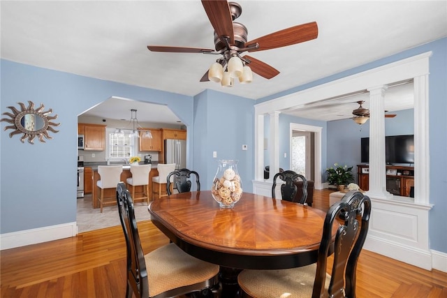 dining space with decorative columns, light hardwood / wood-style floors, and ceiling fan