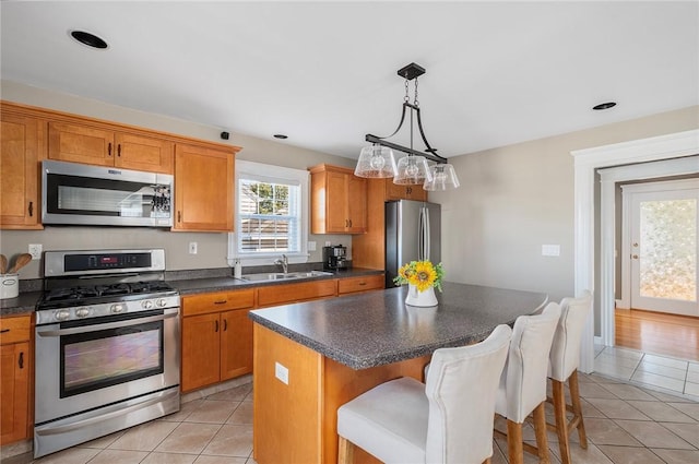 kitchen featuring light tile patterned flooring, sink, a breakfast bar area, a kitchen island, and stainless steel appliances