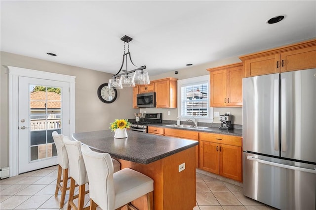 kitchen featuring light tile patterned flooring, a kitchen island, appliances with stainless steel finishes, sink, and hanging light fixtures