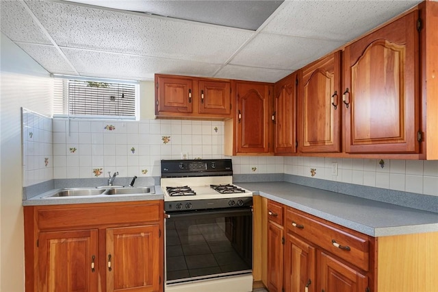 kitchen with sink, backsplash, a paneled ceiling, and gas stove