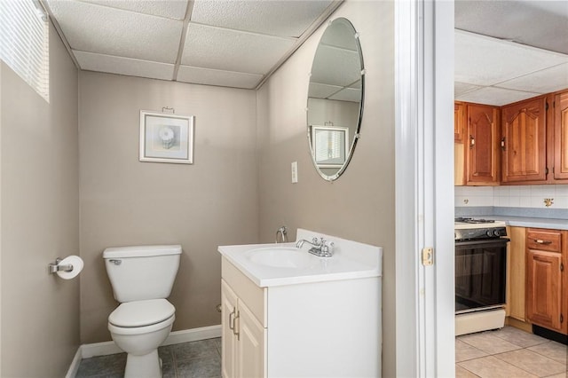 bathroom featuring backsplash, toilet, tile patterned flooring, and a drop ceiling