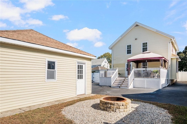 back of property featuring a gazebo and a fire pit