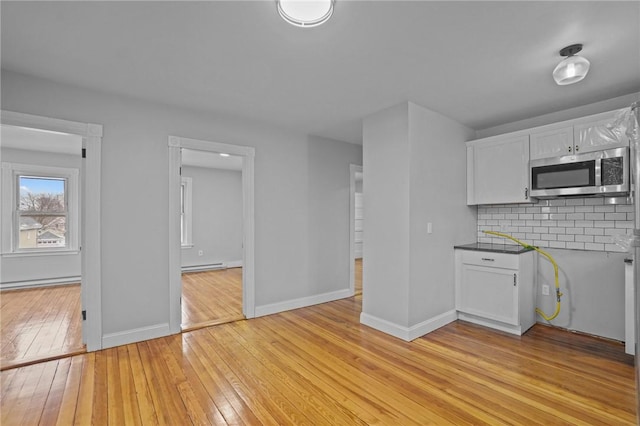 kitchen featuring tasteful backsplash, white cabinetry, a baseboard radiator, and light hardwood / wood-style flooring