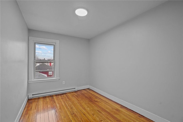 unfurnished room featuring hardwood / wood-style floors and a baseboard heating unit