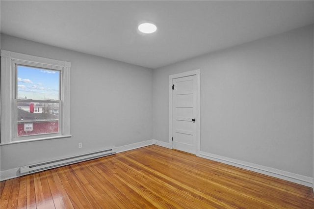 unfurnished room featuring a baseboard heating unit and wood-type flooring