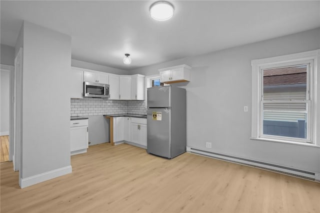 kitchen with light hardwood / wood-style flooring, appliances with stainless steel finishes, white cabinetry, decorative backsplash, and a baseboard radiator