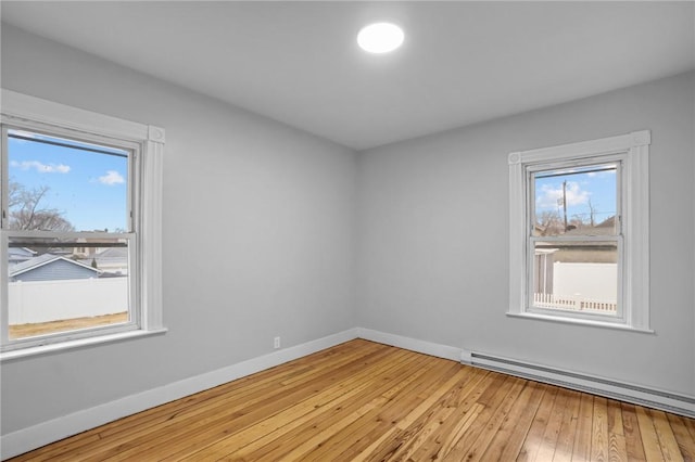 spare room with plenty of natural light, light wood-type flooring, and a baseboard heating unit