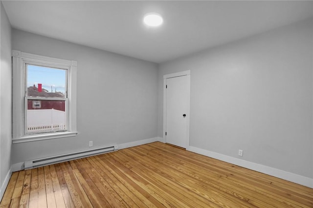 empty room featuring a baseboard radiator and light wood-type flooring