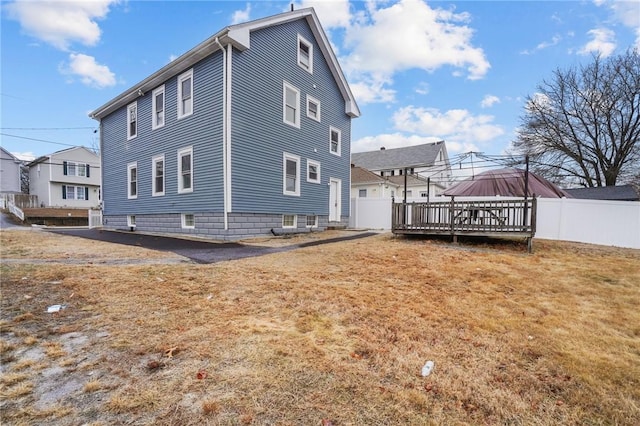 rear view of property with a gazebo, a wooden deck, and a lawn